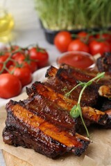 Roasted beef ribs with microgreens, tomatoes and sauce on table, closeup