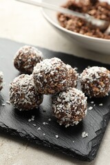 Tasty chocolate candies with nuts and coconut flakes on light table, closeup