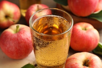 Delicious cider in glass and apples on table, closeup