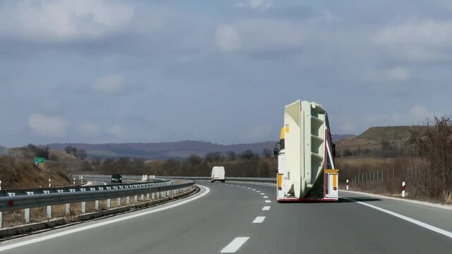 Truck transporting oversized load swimming pool on highway in rural landscape on clear day