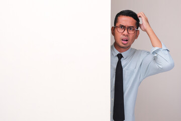 A company employee peeking behind wall scratching his head showing confused face expression