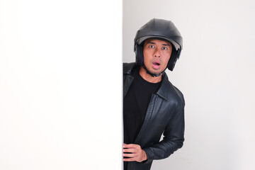 Motorcycle rider wearing helmet peeking behind wall with shocked face expression