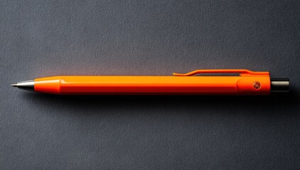 Orange pen on dark surface (1)