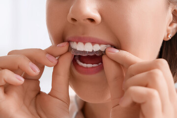 Young woman putting occlusal splint in mouth at home, closeup