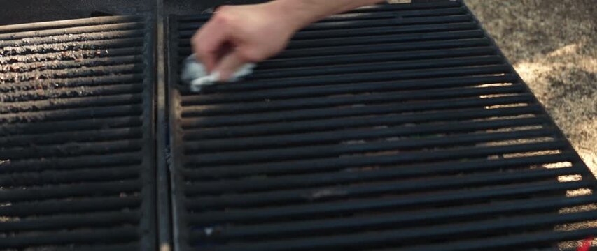 Person cleaning barbecue grill grate before cooking food