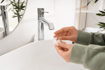 Female hands washing occlusal splint in bathroom, closeup