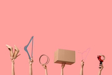 Female hands with wardrobe box, hangers and accessories on pink background