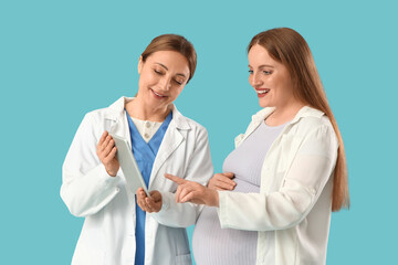 Young pregnant woman and doctor using tablet computer on blue background