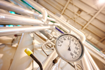 Fototapeta premium Round dial thermometer measuring temperature in an industrial setting during daytime operations