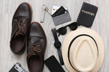 Male traveler's accessories on light wooden floor, top view