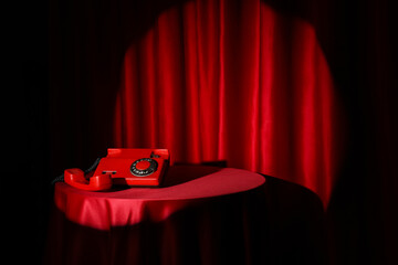 Retro telephone on table near red curtain