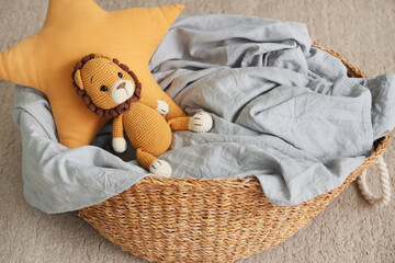 Laundry basket with toy lion and star pillow on carpet in room