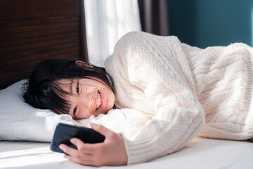 ベッドに寝転がってスマホを使う思春期の少女