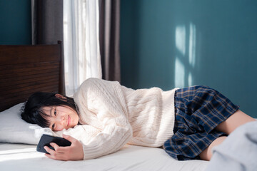 ベッドに寝転がってスマホを使う思春期の少女