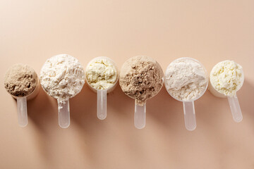 Protein powder in scoops. Different flavours of whey protein powder, top view, copy space.