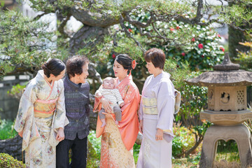 A group of women in traditional Japanese clothing are standing together, one of them holding a baby. Concept of warmth and togetherness, as the women are gathered to celebrate the birth of the baby