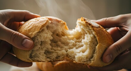 Freshly baked bread being pulled apart by two hands, with steam rising in a cozy kitchen setting