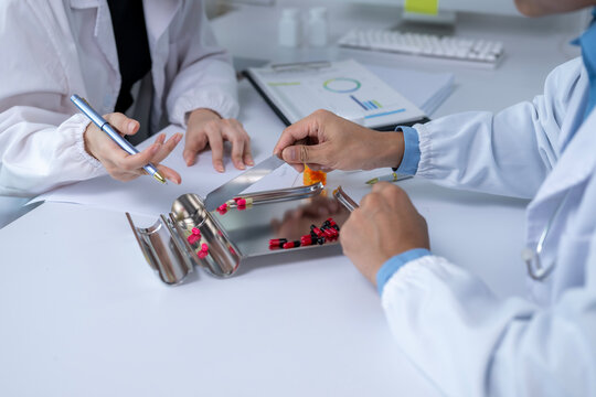 Pharmacists counting and sorting capsules in pharmacy or laboratory