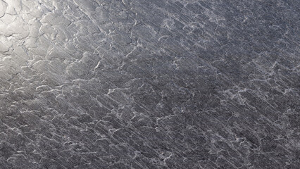 Closeup texture of brushed metal surface with scratches and reflective patterns