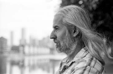 Bearded man with long hair contemplating urban landscape in monochrome