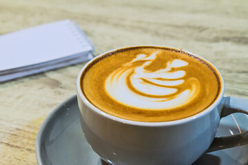 Extreme close up view of cafe latte on the wooden table. grey or gray cup, mug. ceramic. art. brown. white. copy space, empty, free, negative, text, design. blank notepad. digiral nomads. coffee.