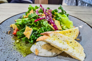 Top view of chicken garlic salad on wooden table. Fresh vegetables in secret garlic sauce serve with chicken grill and garlic bread. Plate. Close up, High angle, above, flat lay. 