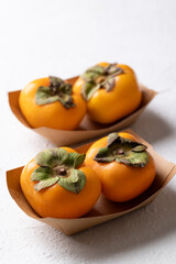 Fresh ripe persimmon in paper bowl on white background, Autumn sweet fruit