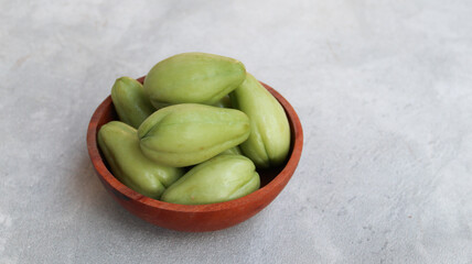 Baby chayote (labu siam) on wooden plate with grey background	
