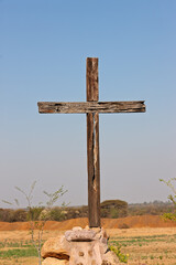 vintage wooden cross crucifix in top of rocks stones outdoors in the nature, blue sky