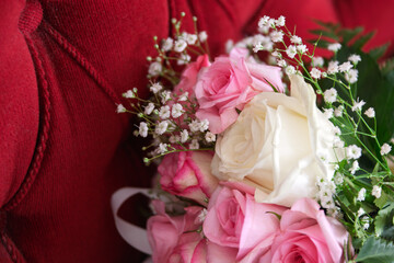 bouquet bunch of white and pink roses sited on a chair with red upholstery