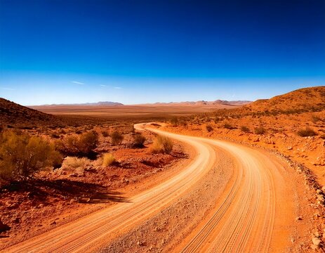  Winding dirt road through a dry desert landscape under a blue sky