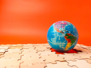 The image shows a colorful globe, which is a puzzle, resting on a surface covered with scattered,...