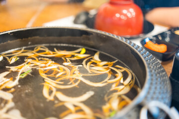 Boiled black soup sukiyaki in pot with ingredients. Close up