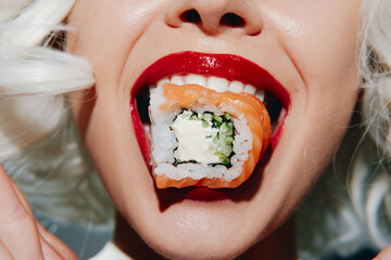 Close-up of a smiling woman with white hair and red lips holding sushi, showcasing vibrant colors...