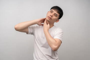 Young man with a pained expression holds his neck, suffering from muscle strain or fatigue due to prolonged sitting. Ideal for healthcare, medical, office syndrome, advertising and lifestyle concept.