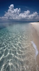 Serene beach scene showcasing crystal clear water rippling onto the white sandy shore under a bright blue sky with puffy white clouds