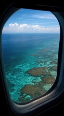 Airplane window view of turquoise ocean waters meeting land under a partly cloudy blue sky during a daytime flight, emphasizing travel and exploration