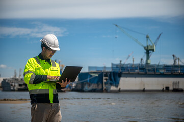 A coast guard is inspecting the shoreline used for mooring large cargo ships through a laptop