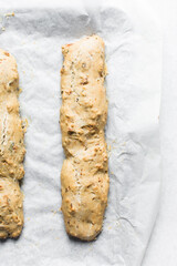 overhead view of bakery savory biscotti log on a parchment lined baking sheet, top view of savory cantucci cookie dough on parchment paper
