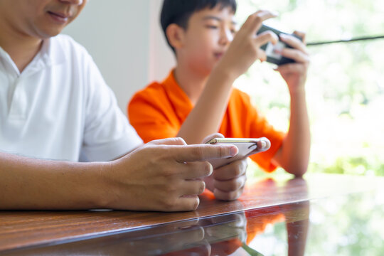Asian father and son with mobile phone playing games together dad spend time with children family.