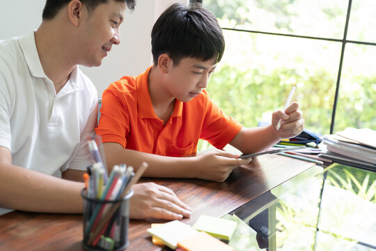 Asian father and son using tablet teaching son to draw
playing with digital tablet at desk fatherhood