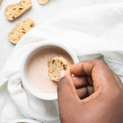 overhead view of slices of savory biscotti in dip, top view of thinly sliced bread chips in sauce, top view of crostini bread slices on marble countertop