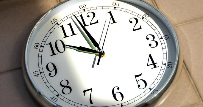 Time-lapse of a classic wall clock with moving shadows and sun rays reflecting across the surface, creating dynamic patterns of light and time flow.
