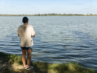 A woman standing on the shore of a lake looking out over the water