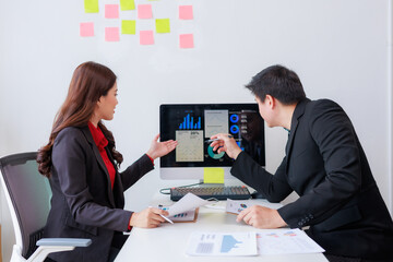Business colleagues collaborating in an office, analyzing financial data on a computer screen while discussing strategies and performance insights