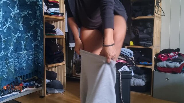 A woman changes into her trainer trousers to feel more comfortable at home, capturing a casual lifestyle moment in a relaxed domestic setting, Switzerland