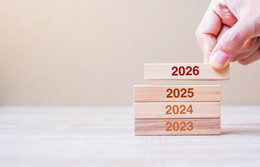 2026 block over 2025 and 2024 wooden building on table background. Business planning, Risk...