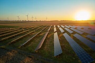 Solar panels and wind turbines in rural landscape at sunset. Concept of renewable energy,...