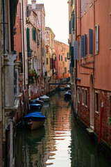 Narrow canal with small boats between historic buildings in Venice, Italy. Concept of travel, tourism and traditional Venetian architecture