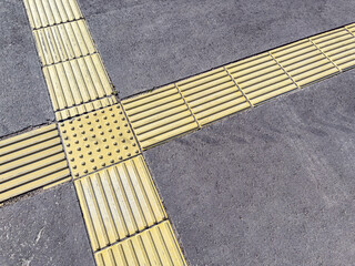 pedestrian pavement detail. yellow tactile anti-slip indicators on city sidewalk.